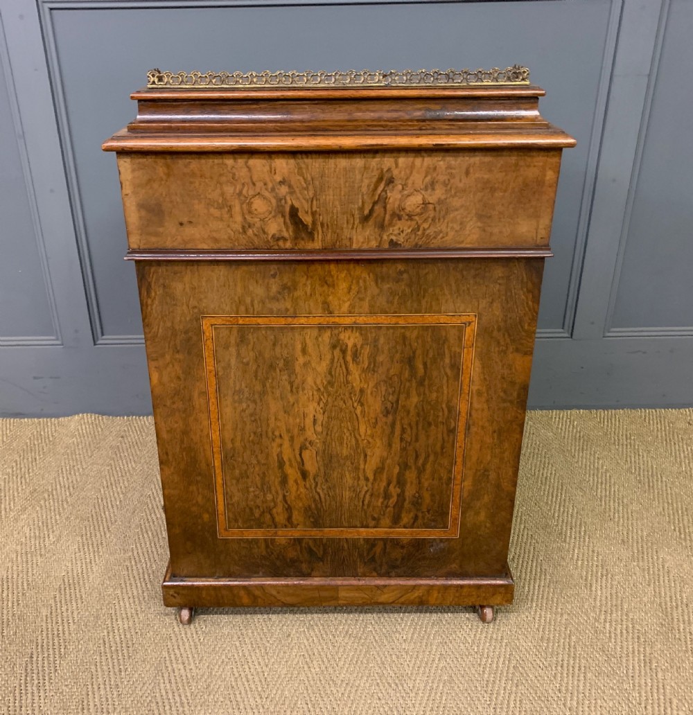 A Victorian burr walnut davenport desk featuring a sloped dark leather inset writing surface, brass gallery rail, side drawers, and fluted column supports. View XXII