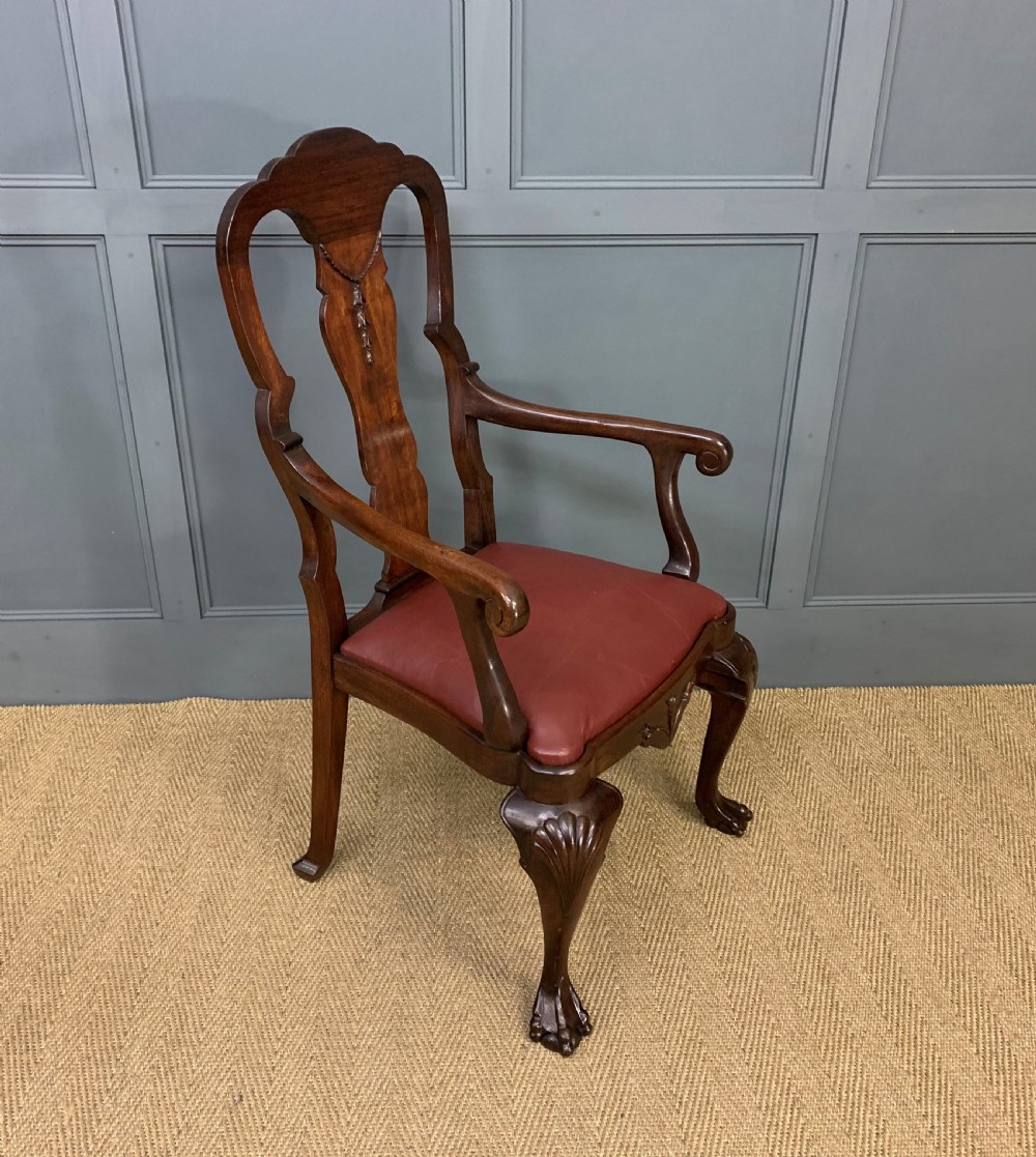 A walnut high-back armchair featuring a carved back splat, reddish-brown leather seat, shaped arms, and carved cabriole legs ending in claw and ball feet. View VI