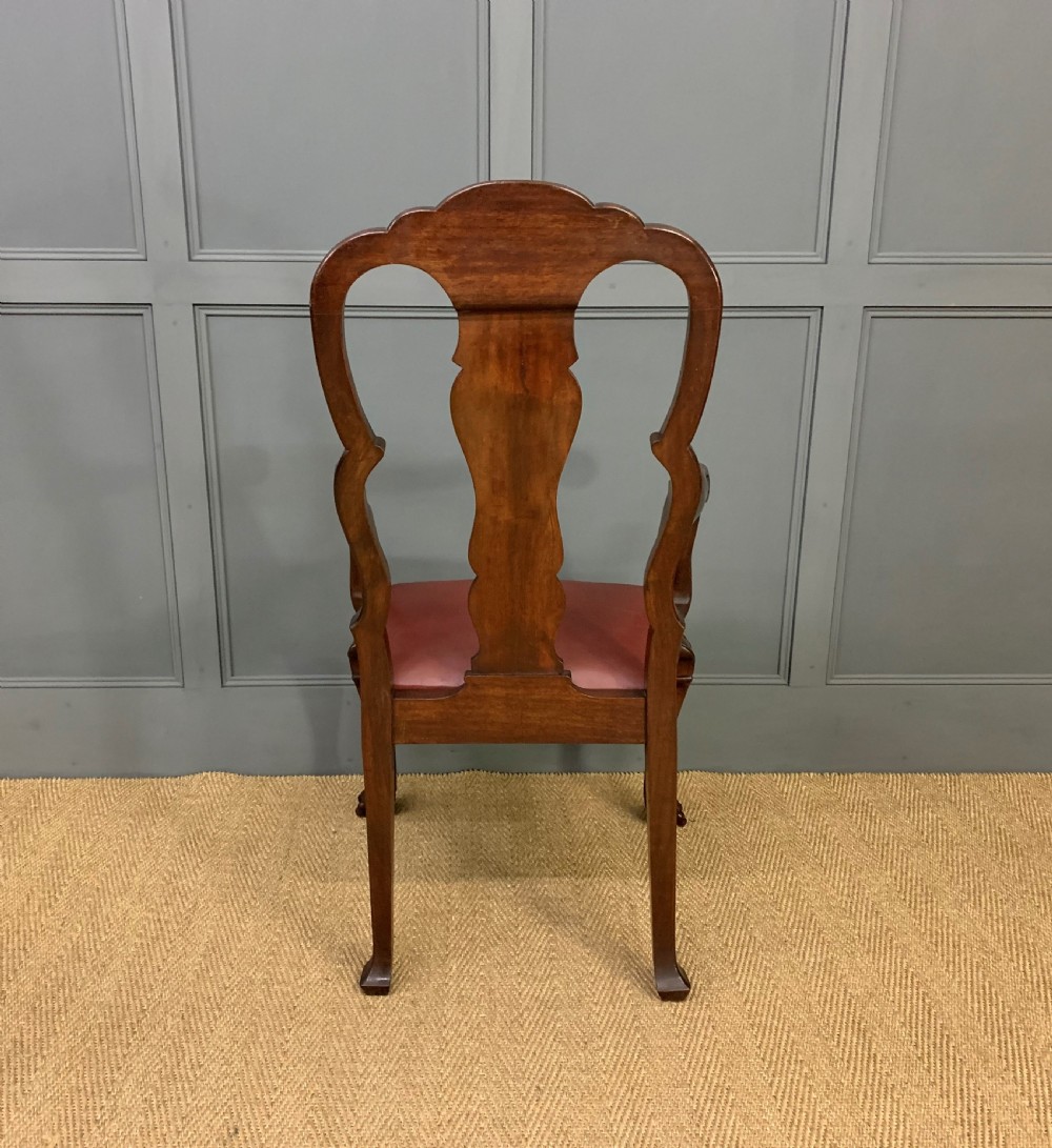 A walnut high-back armchair featuring a carved back splat, reddish-brown leather seat, shaped arms, and carved cabriole legs ending in claw and ball feet. View X