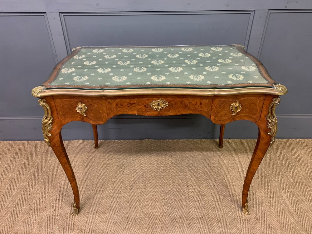 A French Louis XV style bureau plat featuring marquetry floral inlay, gilt-bronze mounts, cabriole legs, and a mint green patterned textile top under protective glass. View II