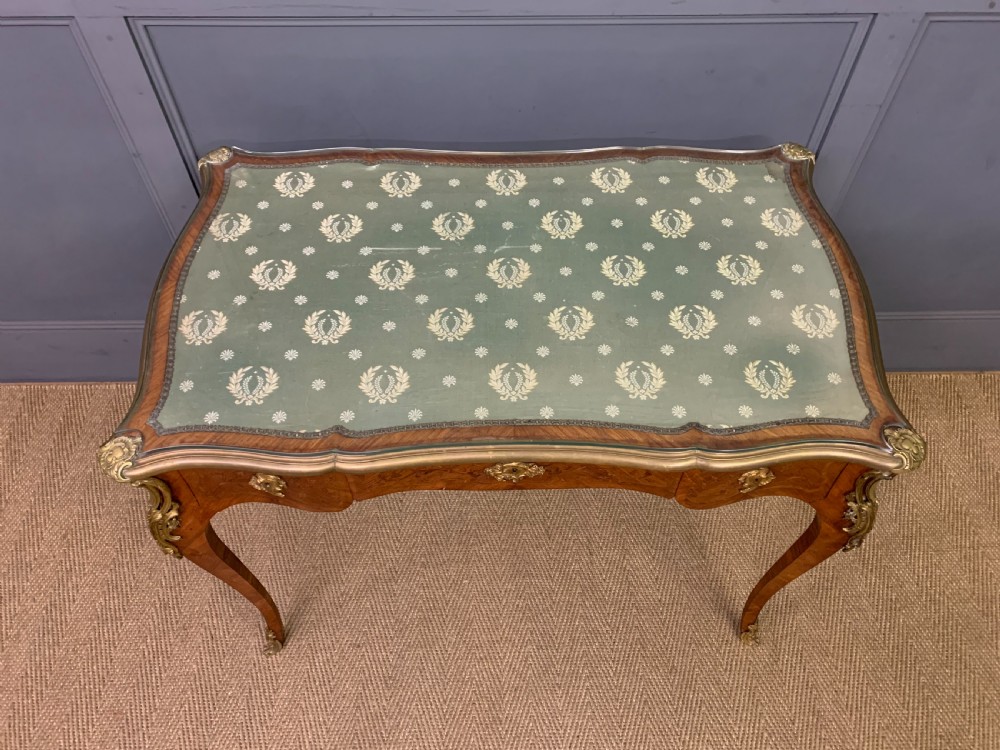 A French Louis XV style bureau plat featuring marquetry floral inlay, gilt-bronze mounts, cabriole legs, and a mint green patterned textile top under protective glass. View IV