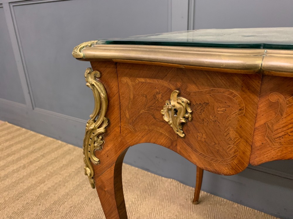 A French Louis XV style bureau plat featuring marquetry floral inlay, gilt-bronze mounts, cabriole legs, and a mint green patterned textile top under protective glass. View V