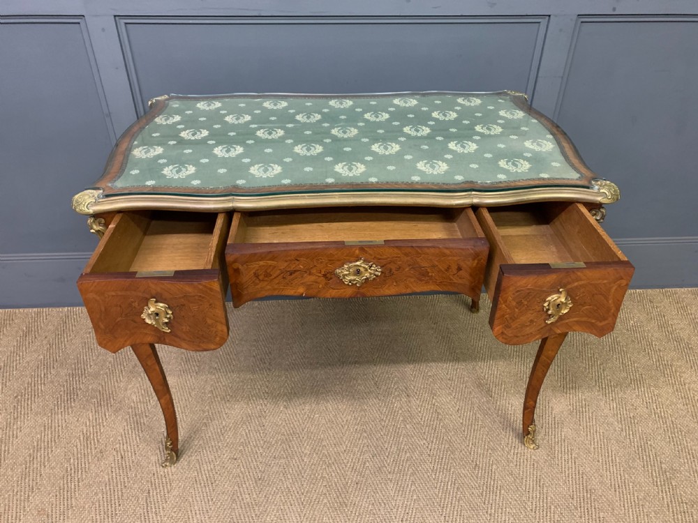 A French Louis XV style bureau plat featuring marquetry floral inlay, gilt-bronze mounts, cabriole legs, and a mint green patterned textile top under protective glass. View X