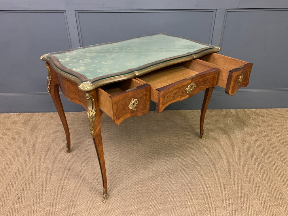 A French Louis XV style bureau plat featuring marquetry floral inlay, gilt-bronze mounts, cabriole legs, and a mint green patterned textile top under protective glass. View XI