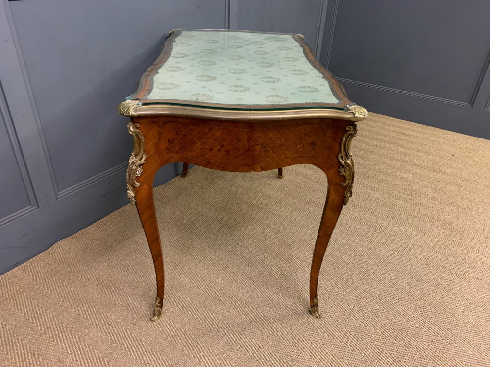 A French Louis XV style bureau plat featuring marquetry floral inlay, gilt-bronze mounts, cabriole legs, and a mint green patterned textile top under protective glass. View XIII