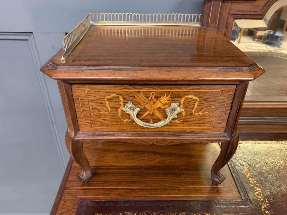 A Victorian mahogany writing desk featuring floral marquetry inlay, a gold-tooled leather insert, a raised superstructure with two drawers and a central mirror, resting on cabriole legs with brass castors. View IX