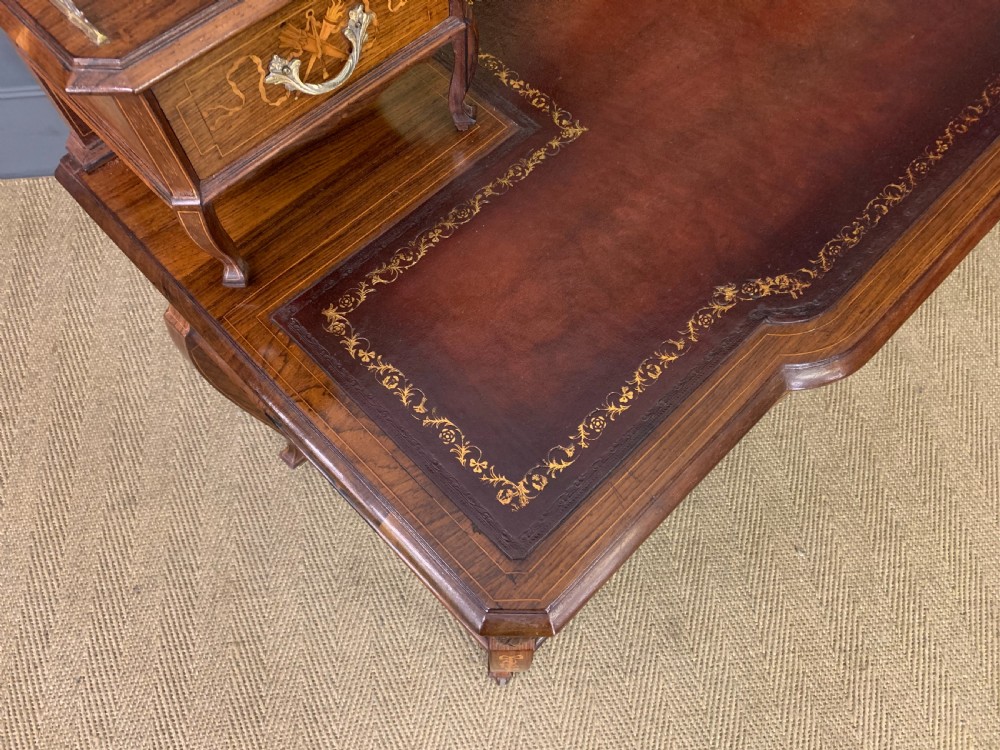 A Victorian mahogany writing desk featuring floral marquetry inlay, a gold-tooled leather insert, a raised superstructure with two drawers and a central mirror, resting on cabriole legs with brass castors. View XV