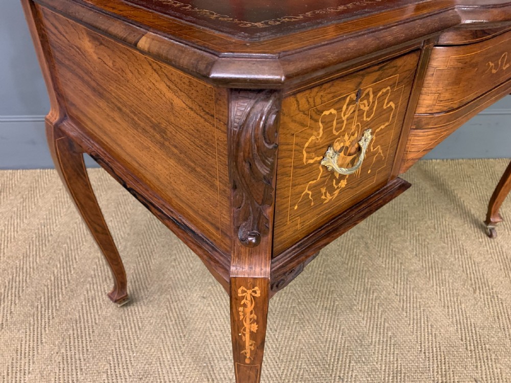 A Victorian mahogany writing desk featuring floral marquetry inlay, a gold-tooled leather insert, a raised superstructure with two drawers and a central mirror, resting on cabriole legs with brass castors. View XVI