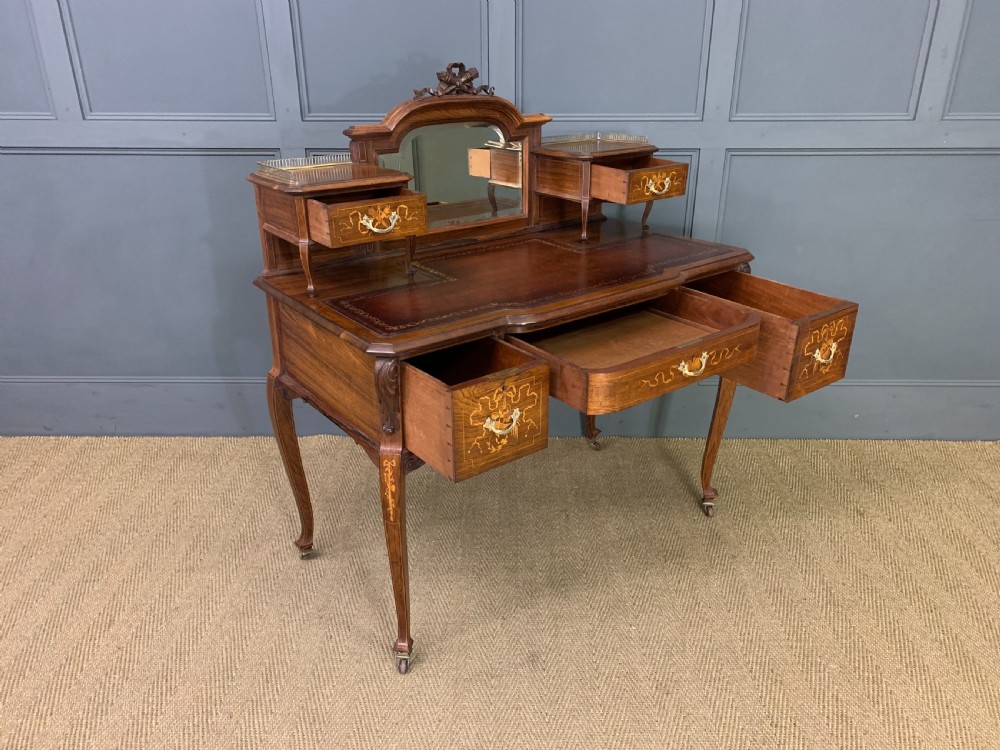 A Victorian mahogany writing desk featuring floral marquetry inlay, a gold-tooled leather insert, a raised superstructure with two drawers and a central mirror, resting on cabriole legs with brass castors. View XVIII