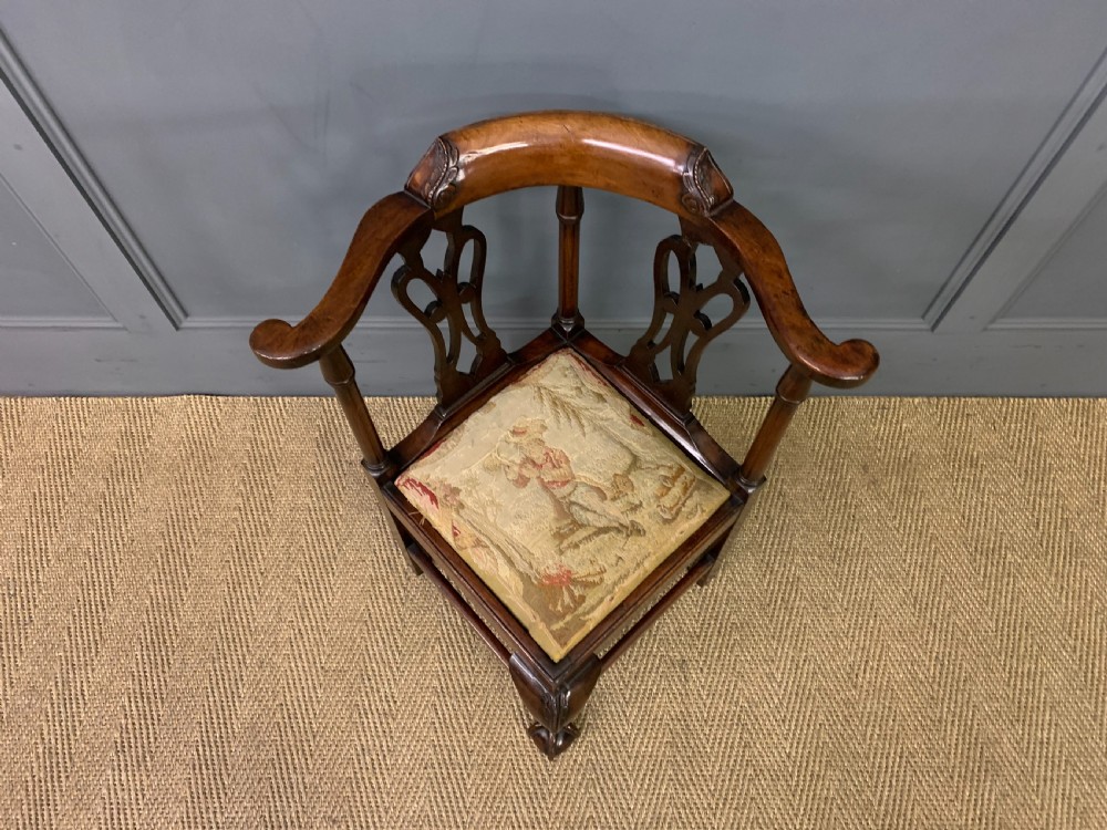 A Georgian style walnut corner chair with a curved crest rail, pierced back splats, a tapestry seat pad, and a central cabriole front leg ending in a claw and ball foot. View IV