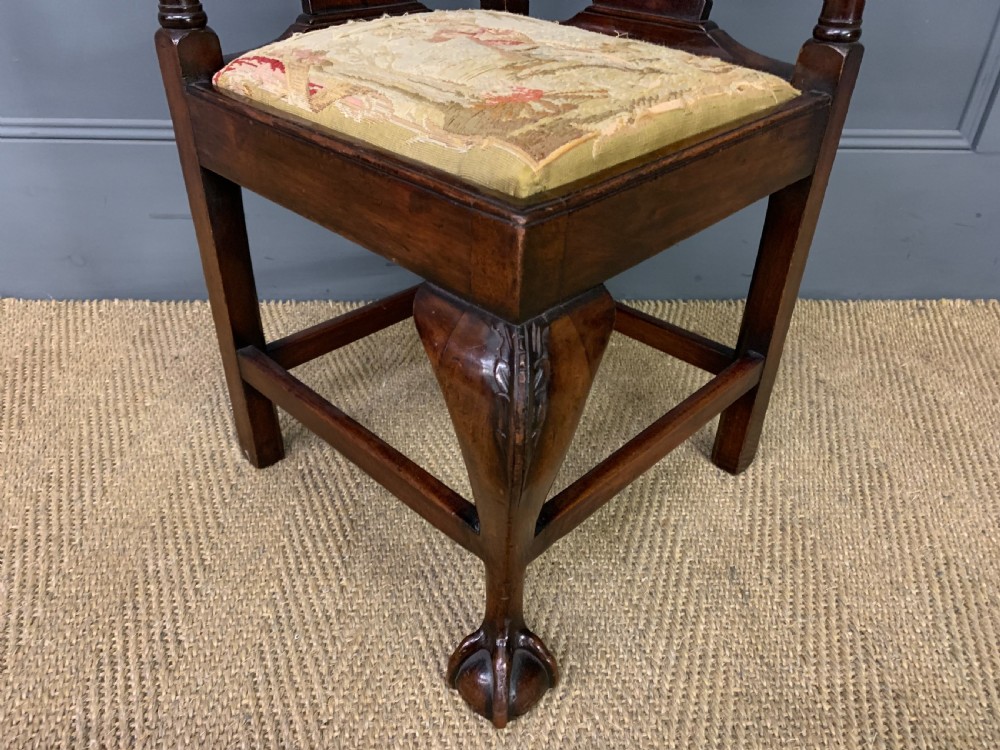 A Georgian style walnut corner chair with a curved crest rail, pierced back splats, a tapestry seat pad, and a central cabriole front leg ending in a claw and ball foot. View V