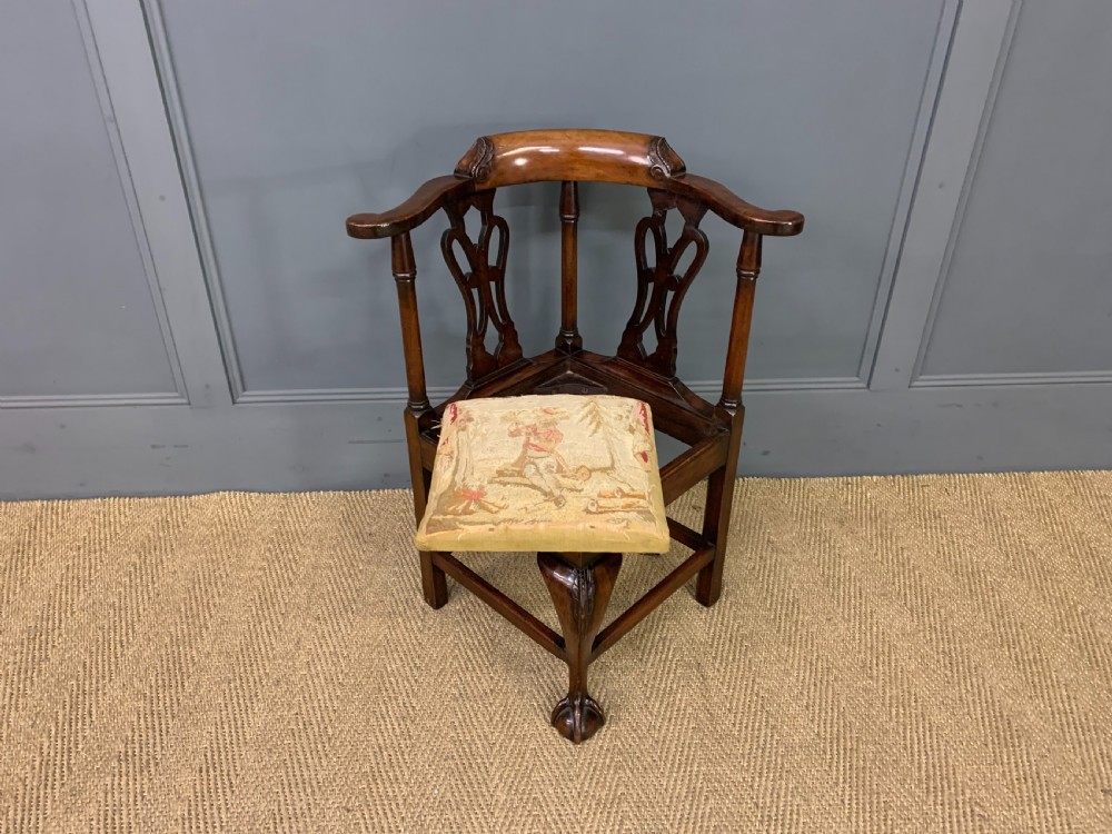 A Georgian style walnut corner chair with a curved crest rail, pierced back splats, a tapestry seat pad, and a central cabriole front leg ending in a claw and ball foot. View VI