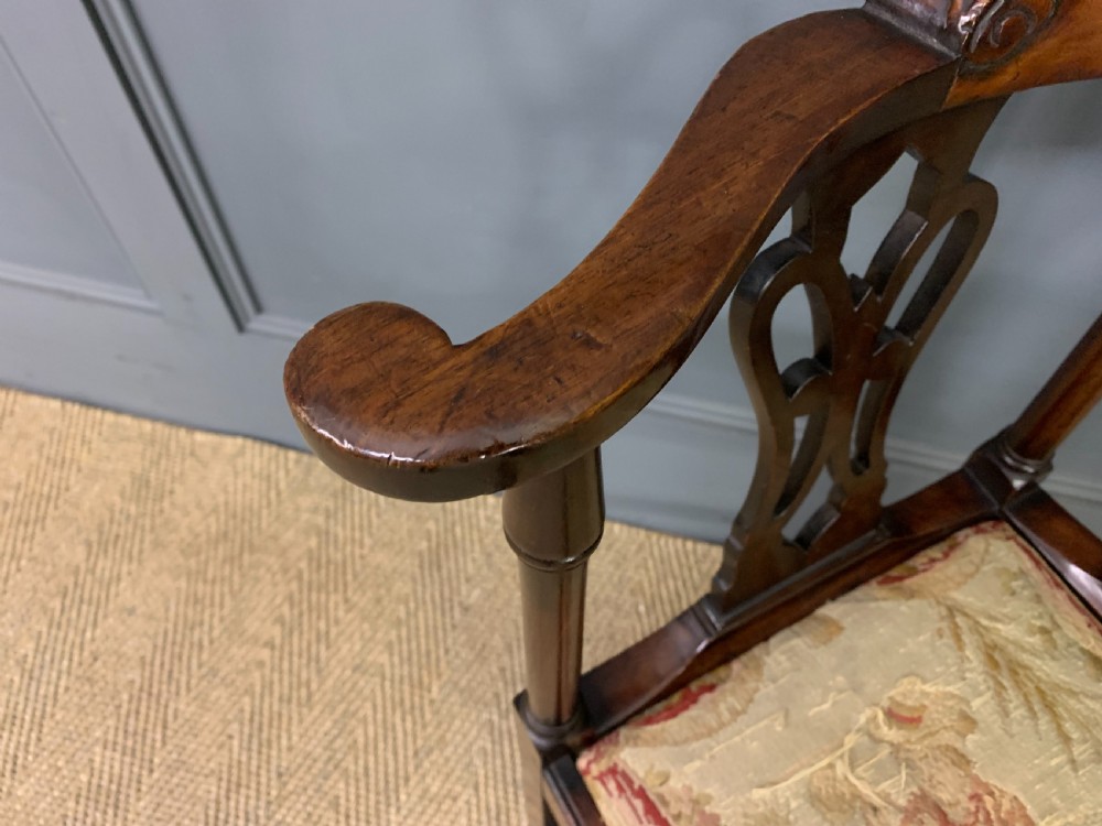 A Georgian style walnut corner chair with a curved crest rail, pierced back splats, a tapestry seat pad, and a central cabriole front leg ending in a claw and ball foot. View VII