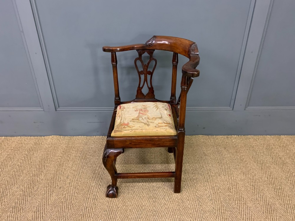 A Georgian style walnut corner chair with a curved crest rail, pierced back splats, a tapestry seat pad, and a central cabriole front leg ending in a claw and ball foot. View IX