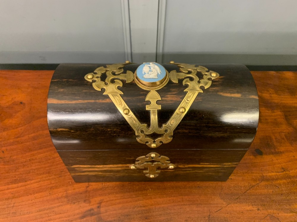 A Victorian dome-topped stationery casket crafted from dark variegated coromandel wood, decorated with pierced brass strapwork and a blue and white ceramic cameo inset. View IV