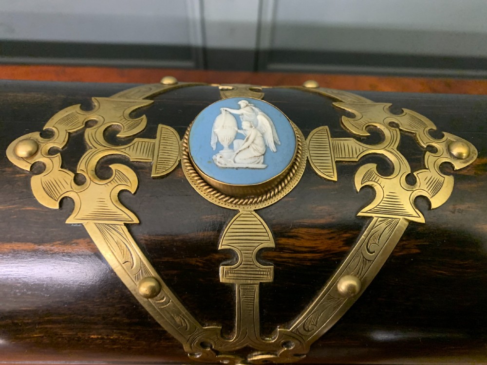 A Victorian dome-topped stationery casket crafted from dark variegated coromandel wood, decorated with pierced brass strapwork and a blue and white ceramic cameo inset. View V