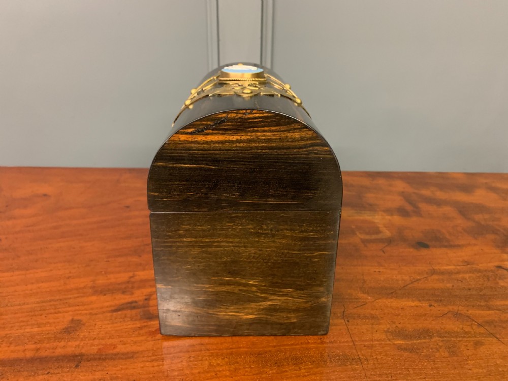 A Victorian dome-topped stationery casket crafted from dark variegated coromandel wood, decorated with pierced brass strapwork and a blue and white ceramic cameo inset. View VII