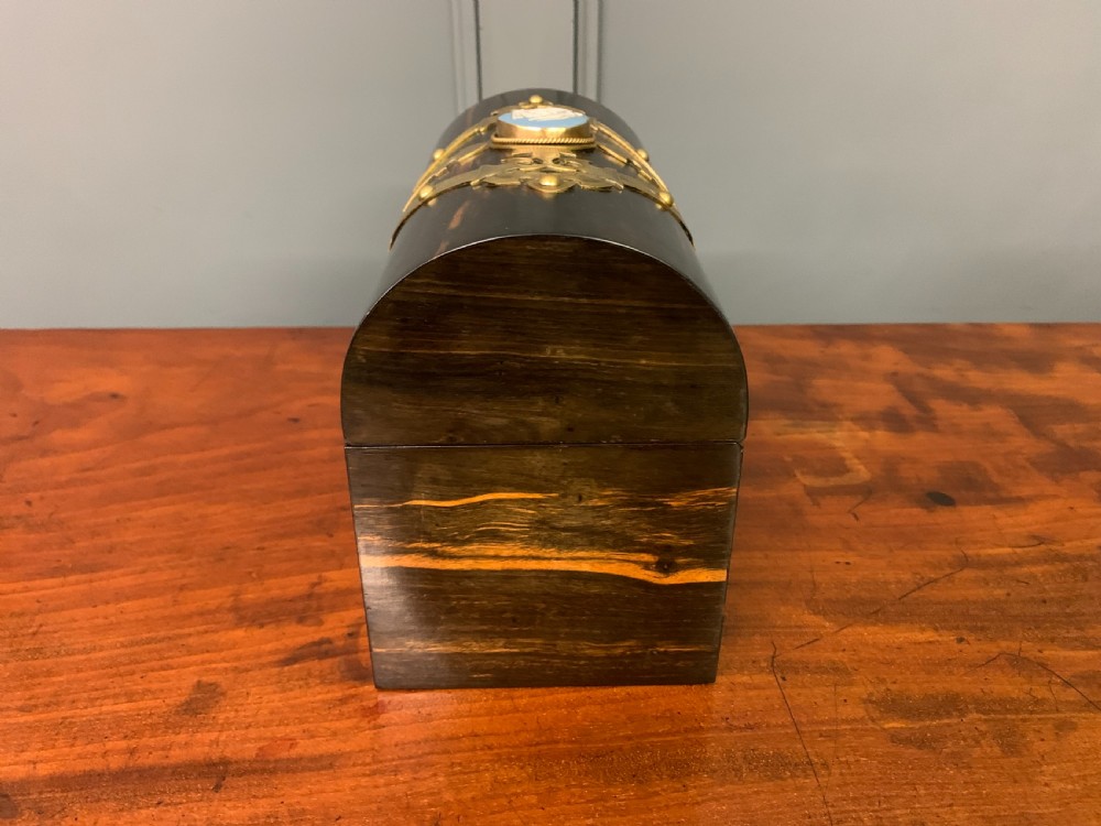 A Victorian dome-topped stationery casket crafted from dark variegated coromandel wood, decorated with pierced brass strapwork and a blue and white ceramic cameo inset. View VIII