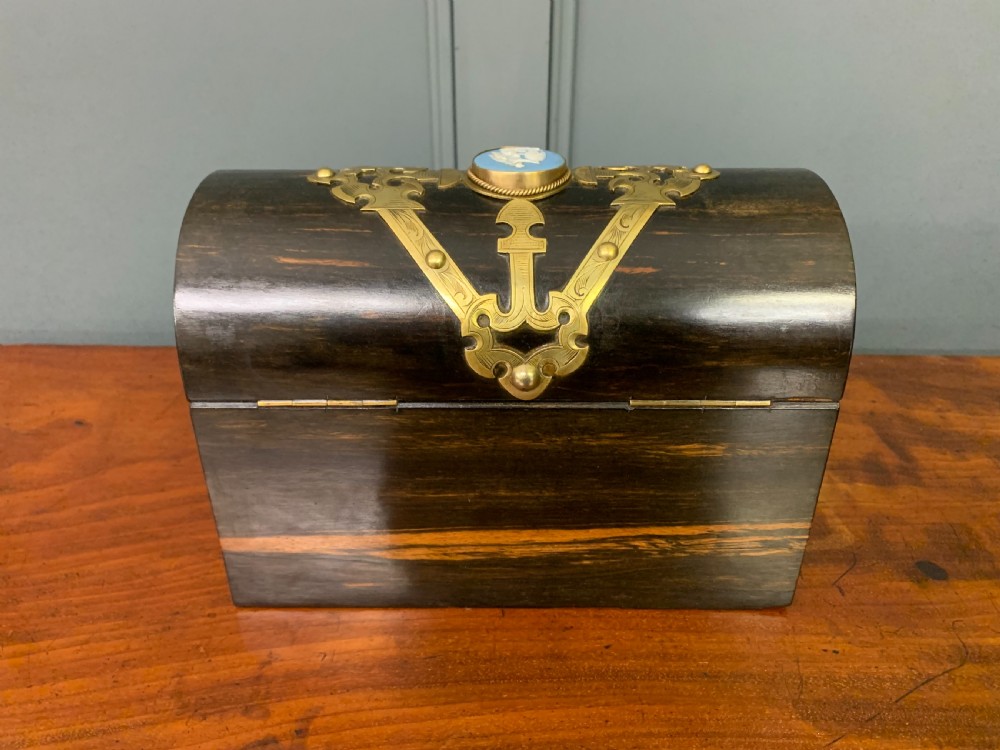 A Victorian dome-topped stationery casket crafted from dark variegated coromandel wood, decorated with pierced brass strapwork and a blue and white ceramic cameo inset. View IX