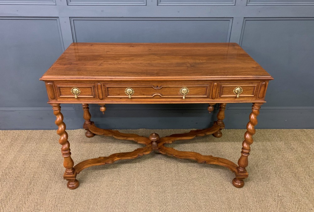 A rectangular walnut side table featuring three drawers with brass teardrop drop-handles, spiral barley twist legs, and a serpentine X-stretcher with a central turned finial.