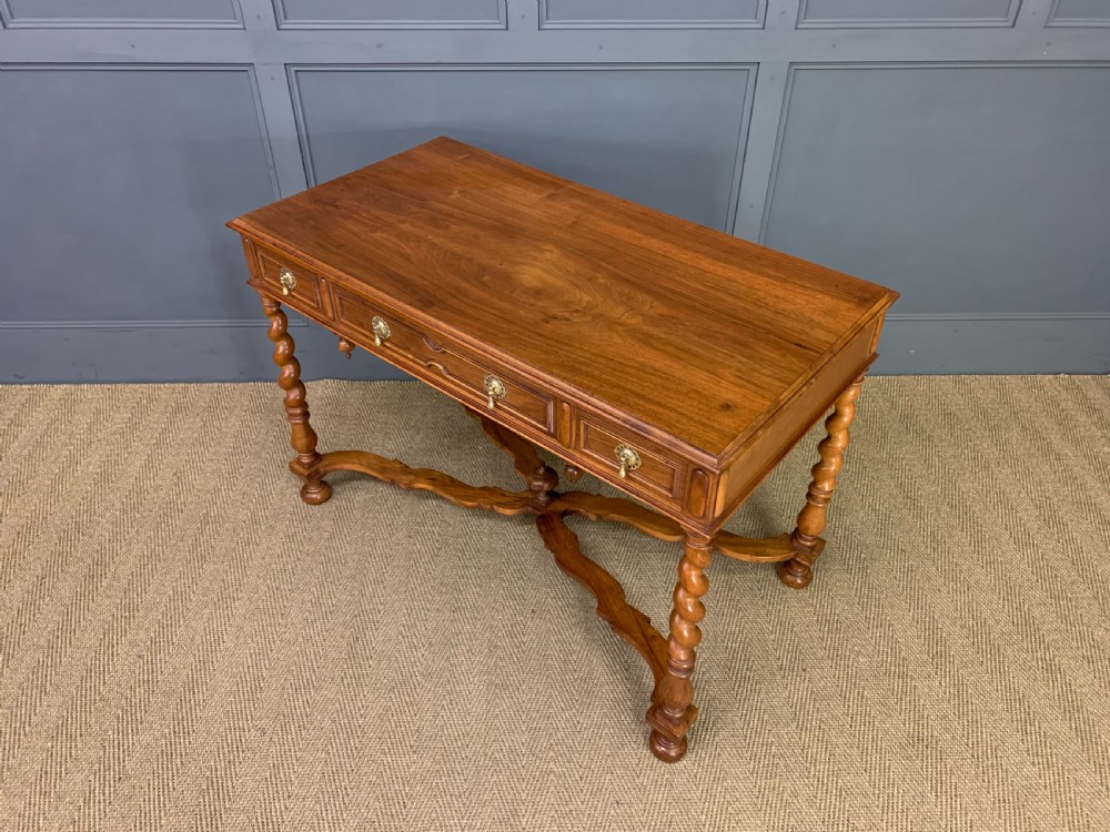 A rectangular walnut side table featuring three drawers with brass teardrop drop-handles, spiral barley twist legs, and a serpentine X-stretcher with a central turned finial. View XVI
