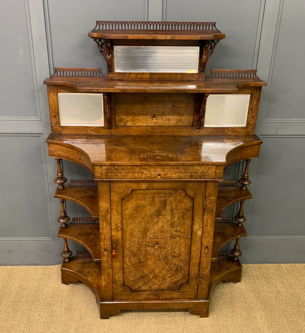 A Victorian burr walnut chiffonier featuring a central cabinet door with floral marquetry, open side tiers with turned spindles, and an upper structure with mirror panels and gallery railings.