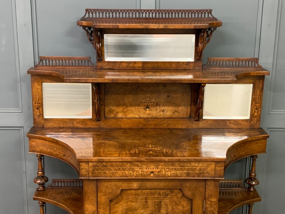 A Victorian burr walnut chiffonier featuring a central cabinet door with floral marquetry, open side tiers with turned spindles, and an upper structure with mirror panels and gallery railings. View II