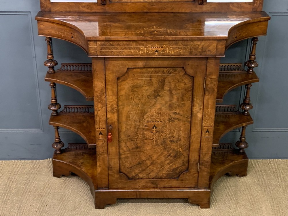A Victorian burr walnut chiffonier featuring a central cabinet door with floral marquetry, open side tiers with turned spindles, and an upper structure with mirror panels and gallery railings. View III