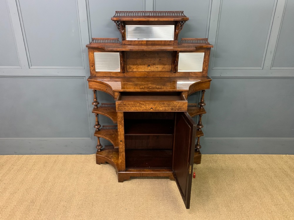 A Victorian burr walnut chiffonier featuring a central cabinet door with floral marquetry, open side tiers with turned spindles, and an upper structure with mirror panels and gallery railings. View IV
