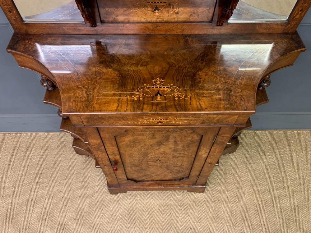 A Victorian burr walnut chiffonier featuring a central cabinet door with floral marquetry, open side tiers with turned spindles, and an upper structure with mirror panels and gallery railings. View VI