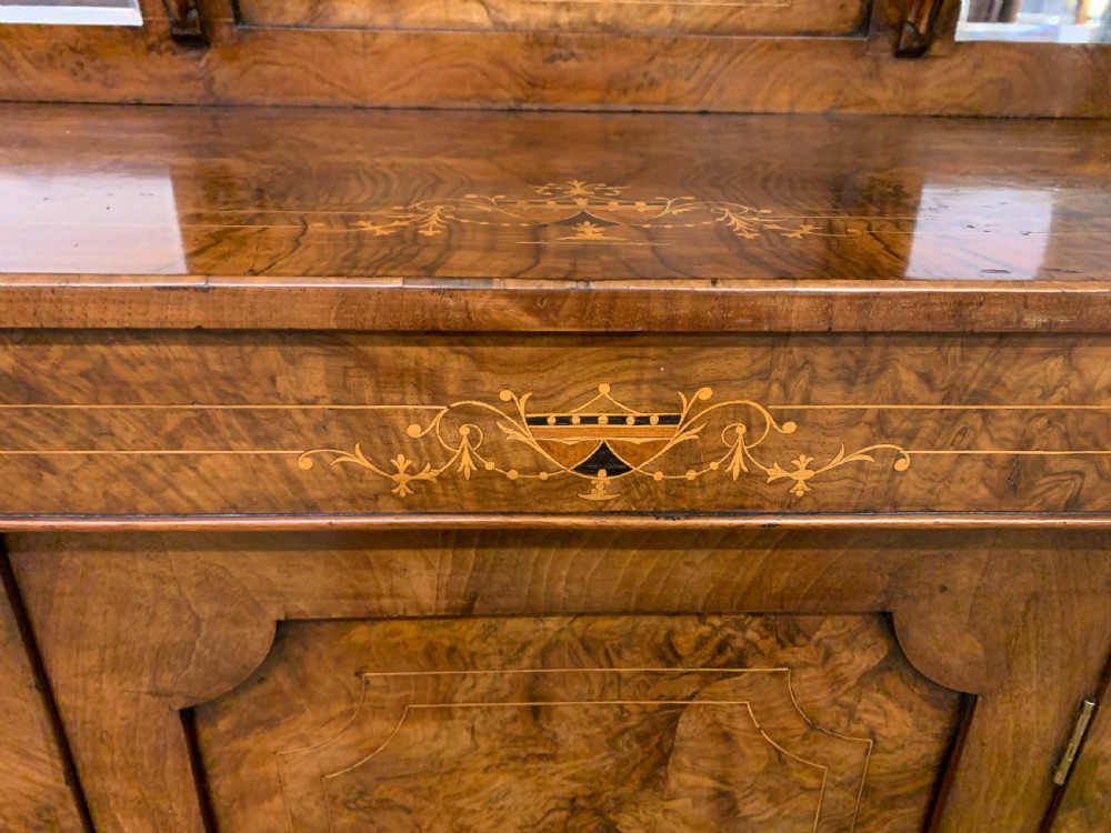 A Victorian burr walnut chiffonier featuring a central cabinet door with floral marquetry, open side tiers with turned spindles, and an upper structure with mirror panels and gallery railings. View VII