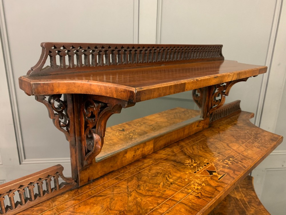 A Victorian burr walnut chiffonier featuring a central cabinet door with floral marquetry, open side tiers with turned spindles, and an upper structure with mirror panels and gallery railings. View XV