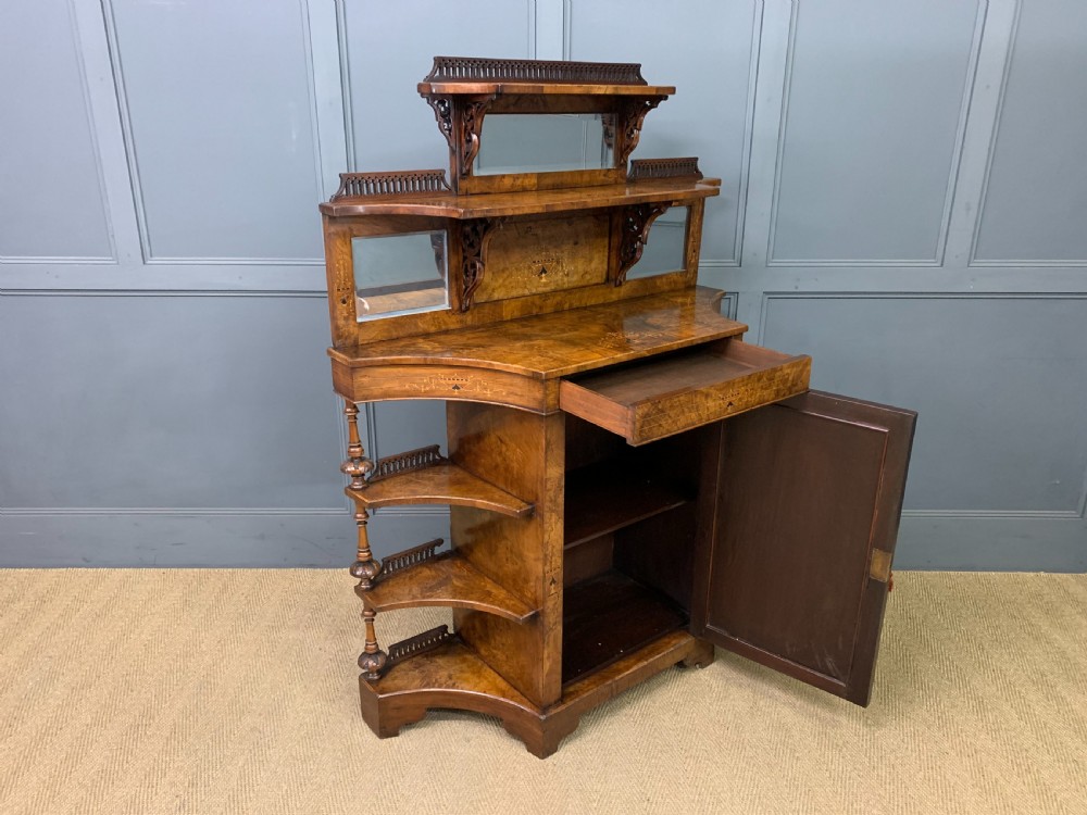 A Victorian burr walnut chiffonier featuring a central cabinet door with floral marquetry, open side tiers with turned spindles, and an upper structure with mirror panels and gallery railings. View XVI