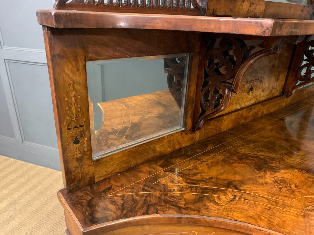 A Victorian burr walnut chiffonier featuring a central cabinet door with floral marquetry, open side tiers with turned spindles, and an upper structure with mirror panels and gallery railings. View XIX