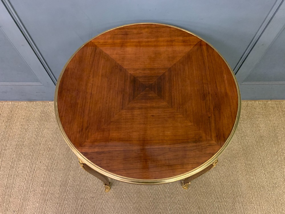 A circular French Louis XV revival centre table featuring quartered rosewood veneers, brass moulding rim, and gilt-bronze mounts on cabriole legs. View III