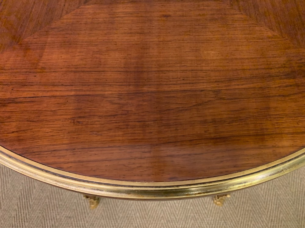 A circular French Louis XV revival centre table featuring quartered rosewood veneers, brass moulding rim, and gilt-bronze mounts on cabriole legs. View IV