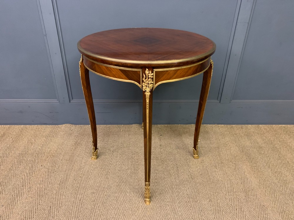 A circular French Louis XV revival centre table featuring quartered rosewood veneers, brass moulding rim, and gilt-bronze mounts on cabriole legs. View VI