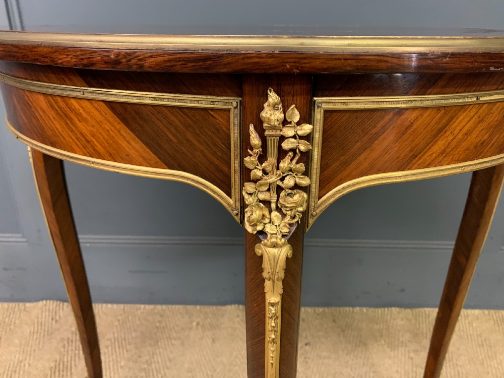 A circular French Louis XV revival centre table featuring quartered rosewood veneers, brass moulding rim, and gilt-bronze mounts on cabriole legs. View VII