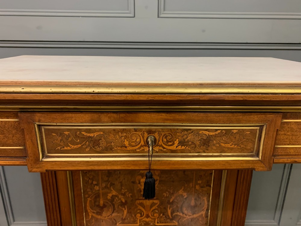 A 19th-century walnut pier table featuring a white marble top, inlaid floral and urn marquetry, fluted front columns with gilt mounts, and a lower open shelf. View IV
