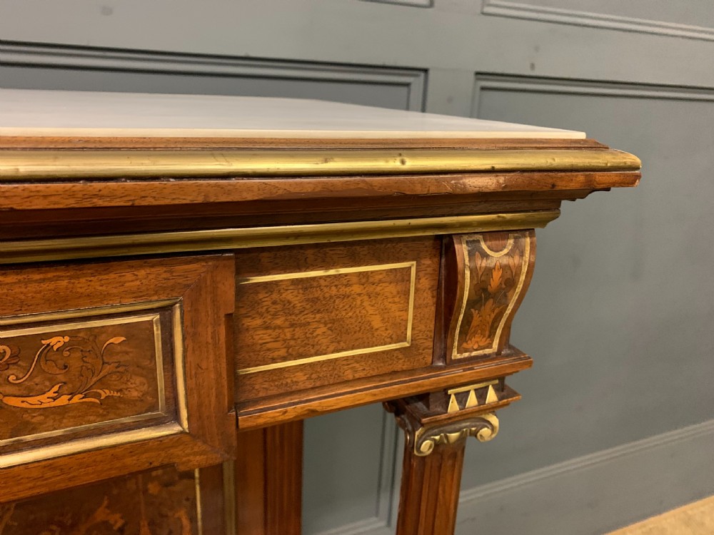 A 19th-century walnut pier table featuring a white marble top, inlaid floral and urn marquetry, fluted front columns with gilt mounts, and a lower open shelf. View V