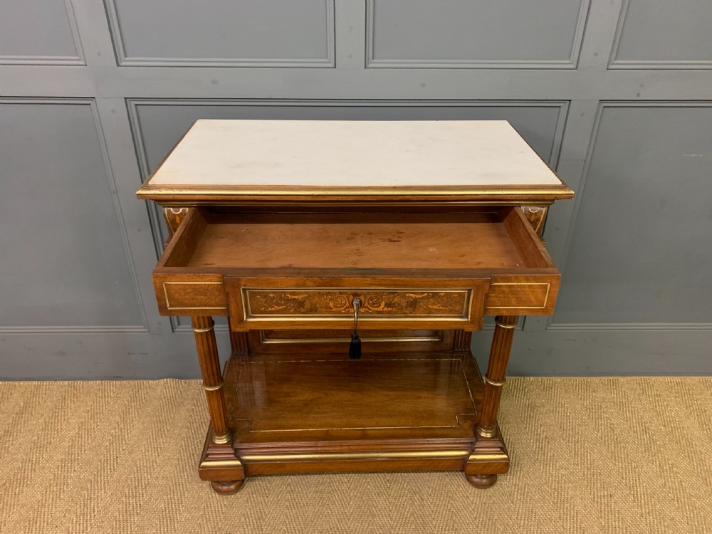 A 19th-century walnut pier table featuring a white marble top, inlaid floral and urn marquetry, fluted front columns with gilt mounts, and a lower open shelf. View XI