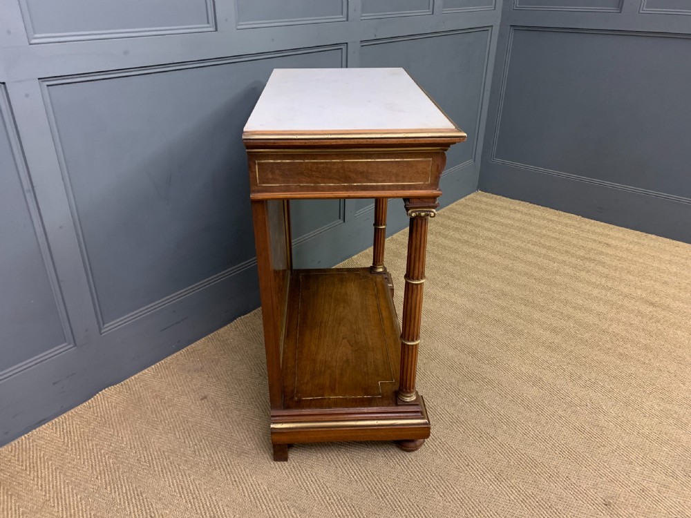 A 19th-century walnut pier table featuring a white marble top, inlaid floral and urn marquetry, fluted front columns with gilt mounts, and a lower open shelf. View XIV