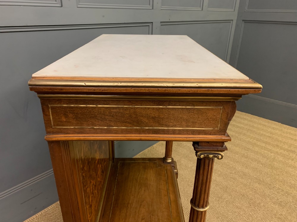 A 19th-century walnut pier table featuring a white marble top, inlaid floral and urn marquetry, fluted front columns with gilt mounts, and a lower open shelf. View XV