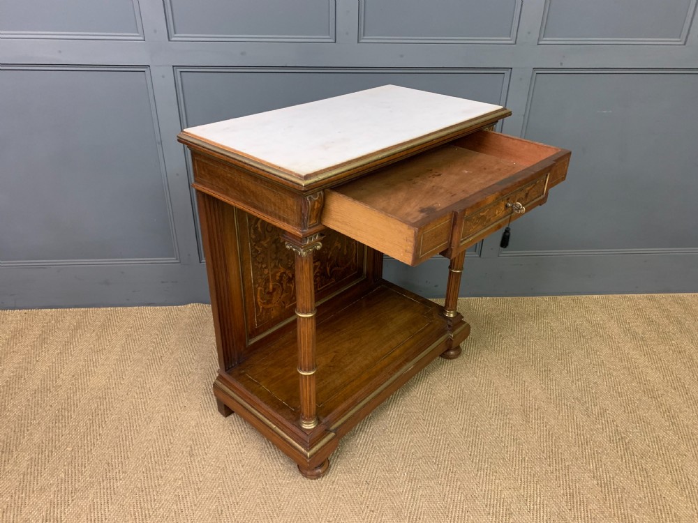 A 19th-century walnut pier table featuring a white marble top, inlaid floral and urn marquetry, fluted front columns with gilt mounts, and a lower open shelf. View XVII