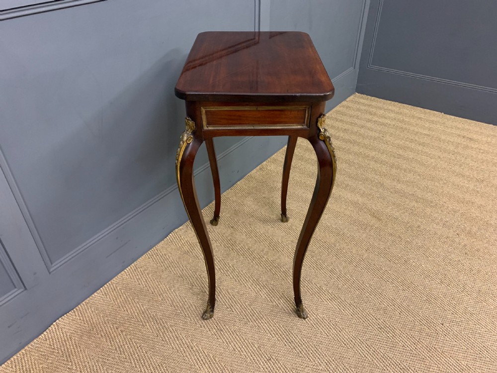 A rectangular dark mahogany side table featuring slender cabriole legs, gilt bronze corner mounts, and a decorative ormolu relief plaque on the frieze. View VI