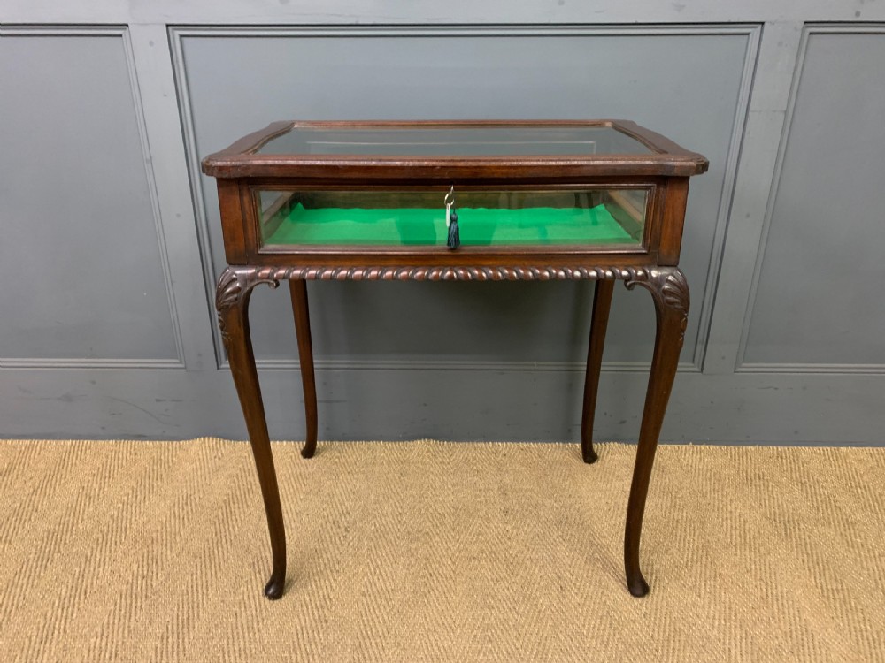 A mahogany bijouterie table featuring a glazed glass top and sides, green fabric interior lining, cabriole legs, and carved shell details on the knees. View III