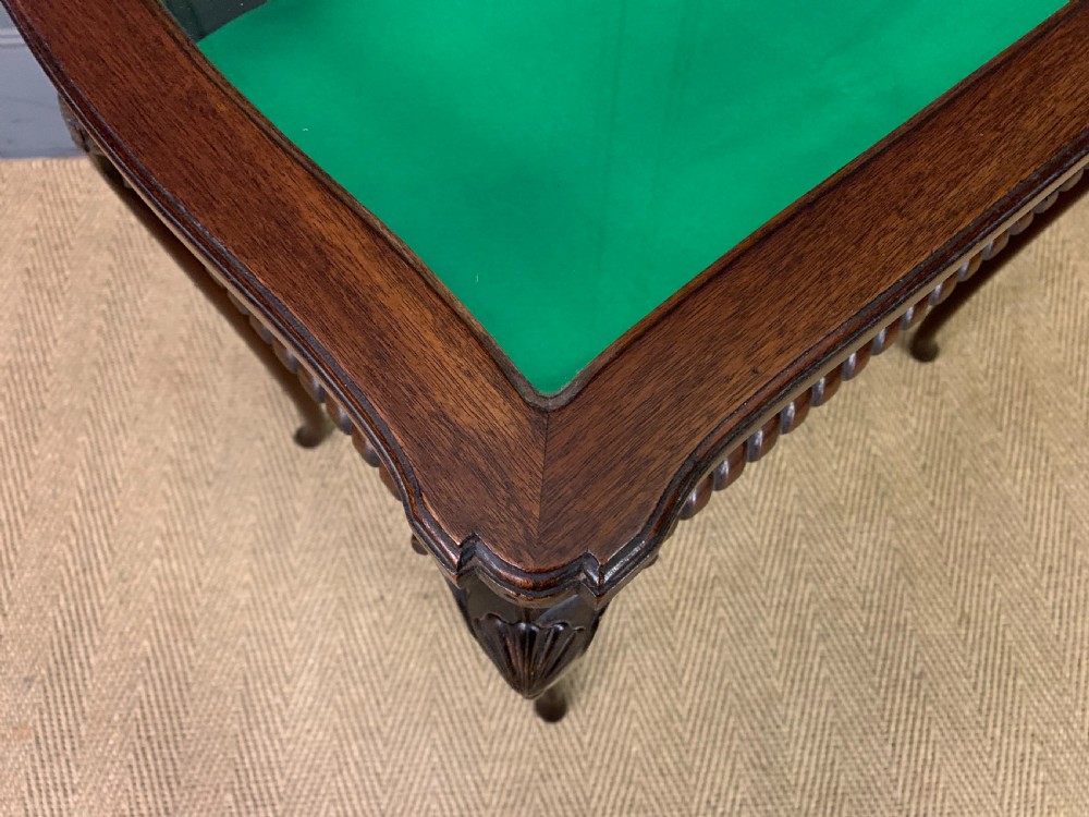 A mahogany bijouterie table featuring a glazed glass top and sides, green fabric interior lining, cabriole legs, and carved shell details on the knees. View V