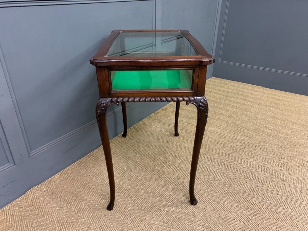 A mahogany bijouterie table featuring a glazed glass top and sides, green fabric interior lining, cabriole legs, and carved shell details on the knees. View VIII