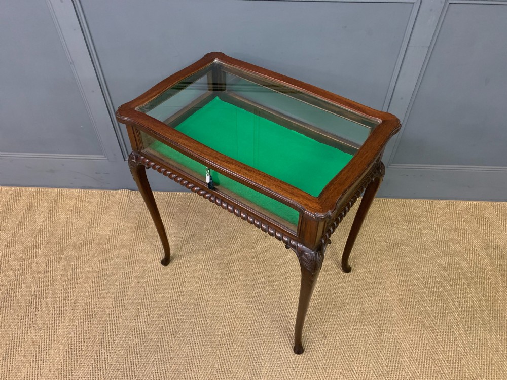 A mahogany bijouterie table featuring a glazed glass top and sides, green fabric interior lining, cabriole legs, and carved shell details on the knees. View XI