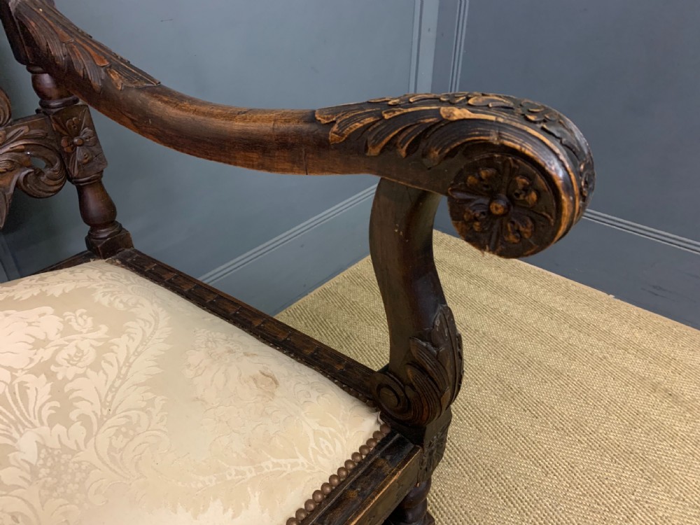 A 19th-century Carolean style walnut three-seat settee featuring barley twist columns, ornate openwork cherub carvings, and cream damask upholstered back panels and seats. View VII